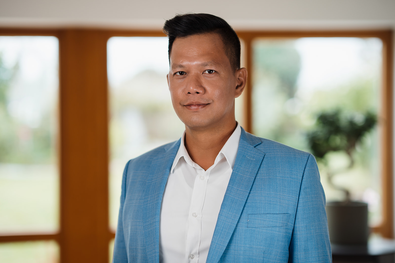 Ein Mann in einem blauen Anzug und einem weißen Hemd steht selbstbewusst da und vermittelt ein professionelles Erscheinungsbild.