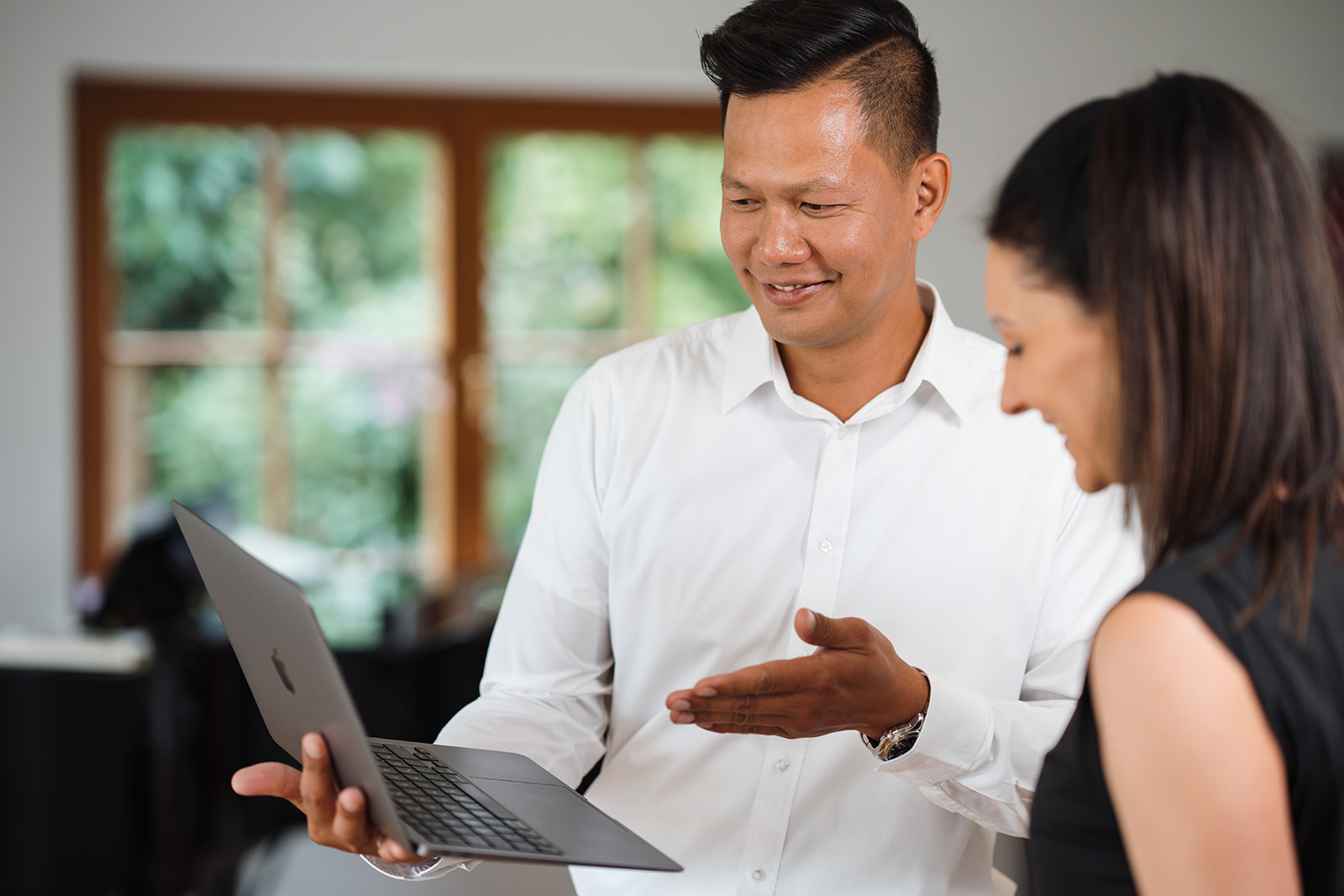 Ein Mann und eine Frau stehen da und schauen auf den Laptop.